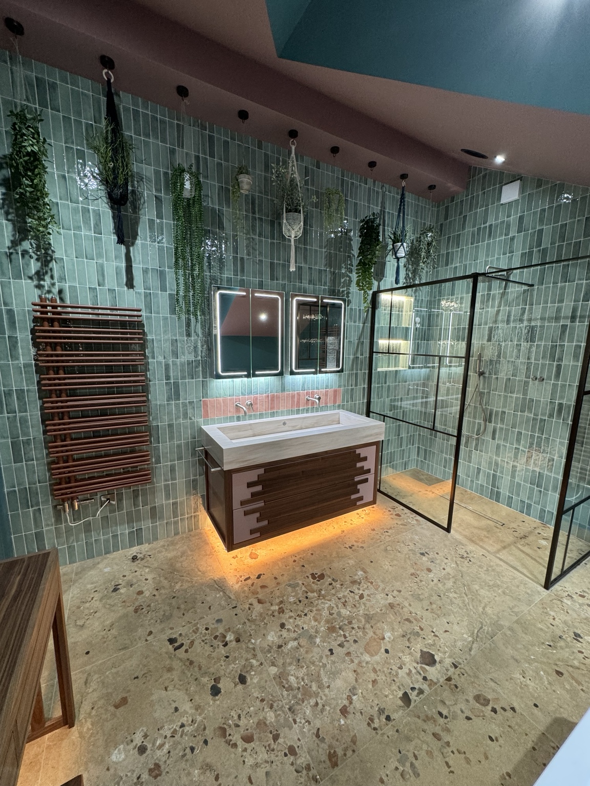 Green tiled bathroom with bespoke basin, lit mirrors and walk-in shower