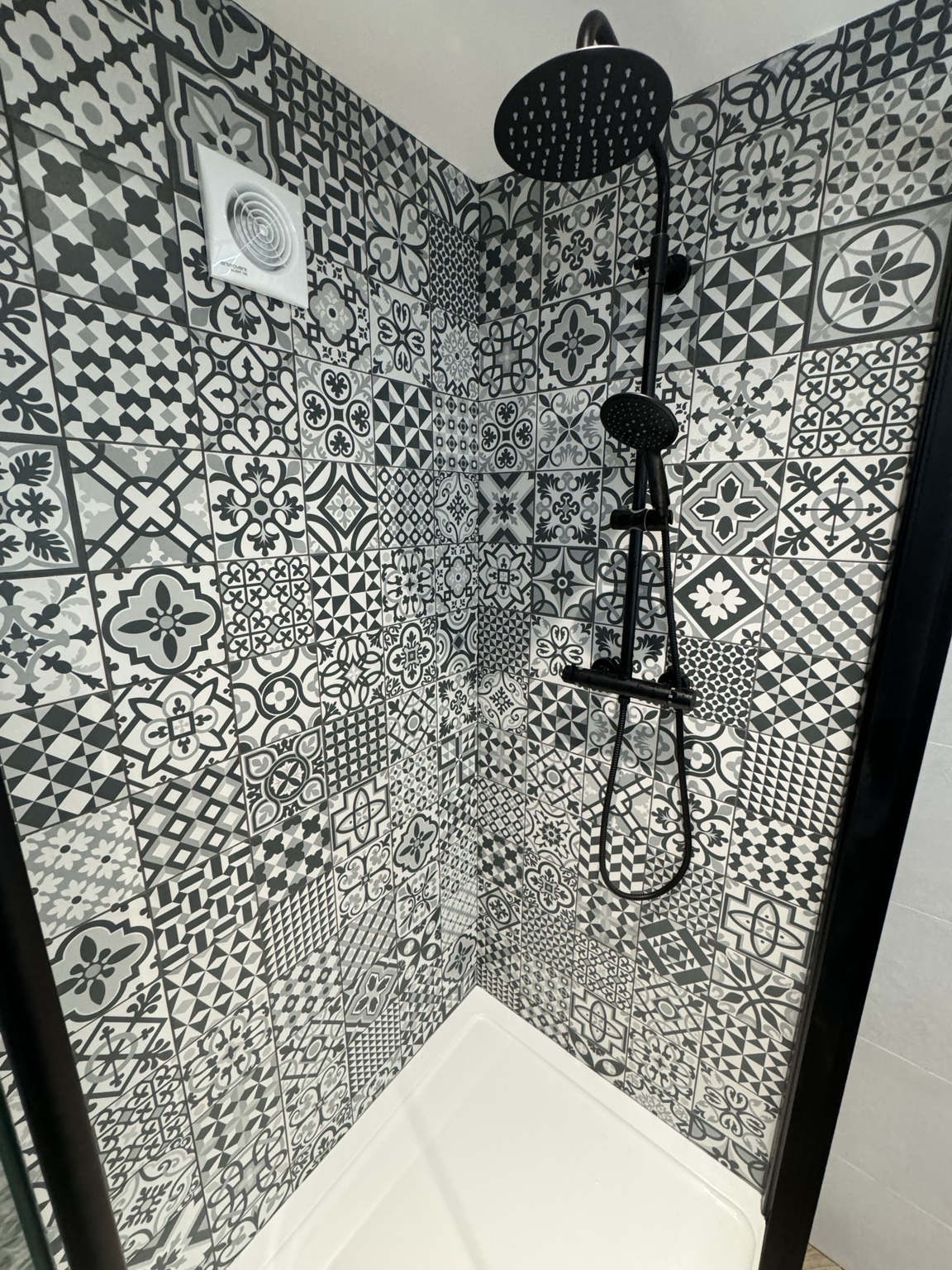 Black shower fittings against patterned feature tiles