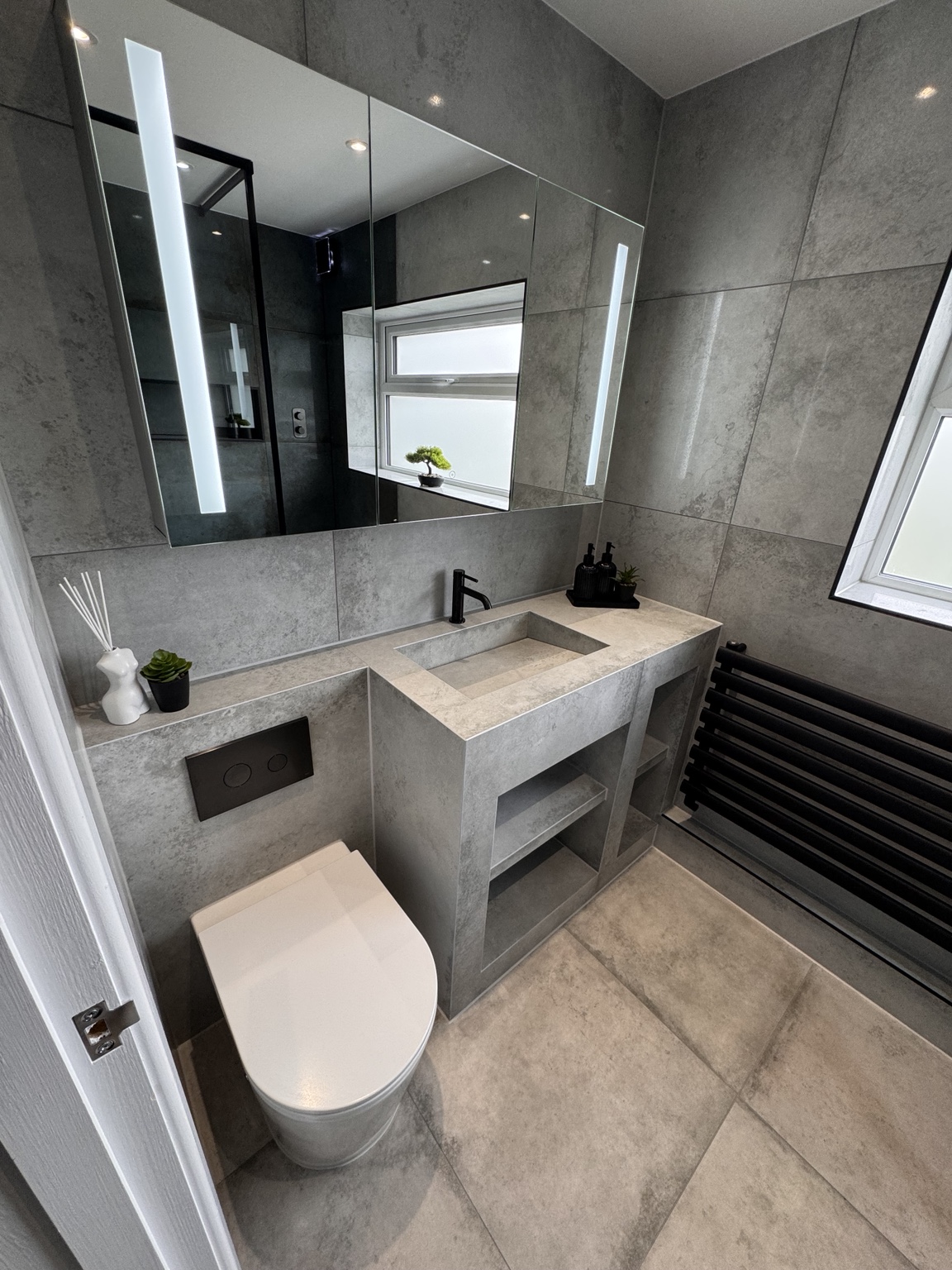 Custom basin and illuminated mirror in the finished tiled bathroom