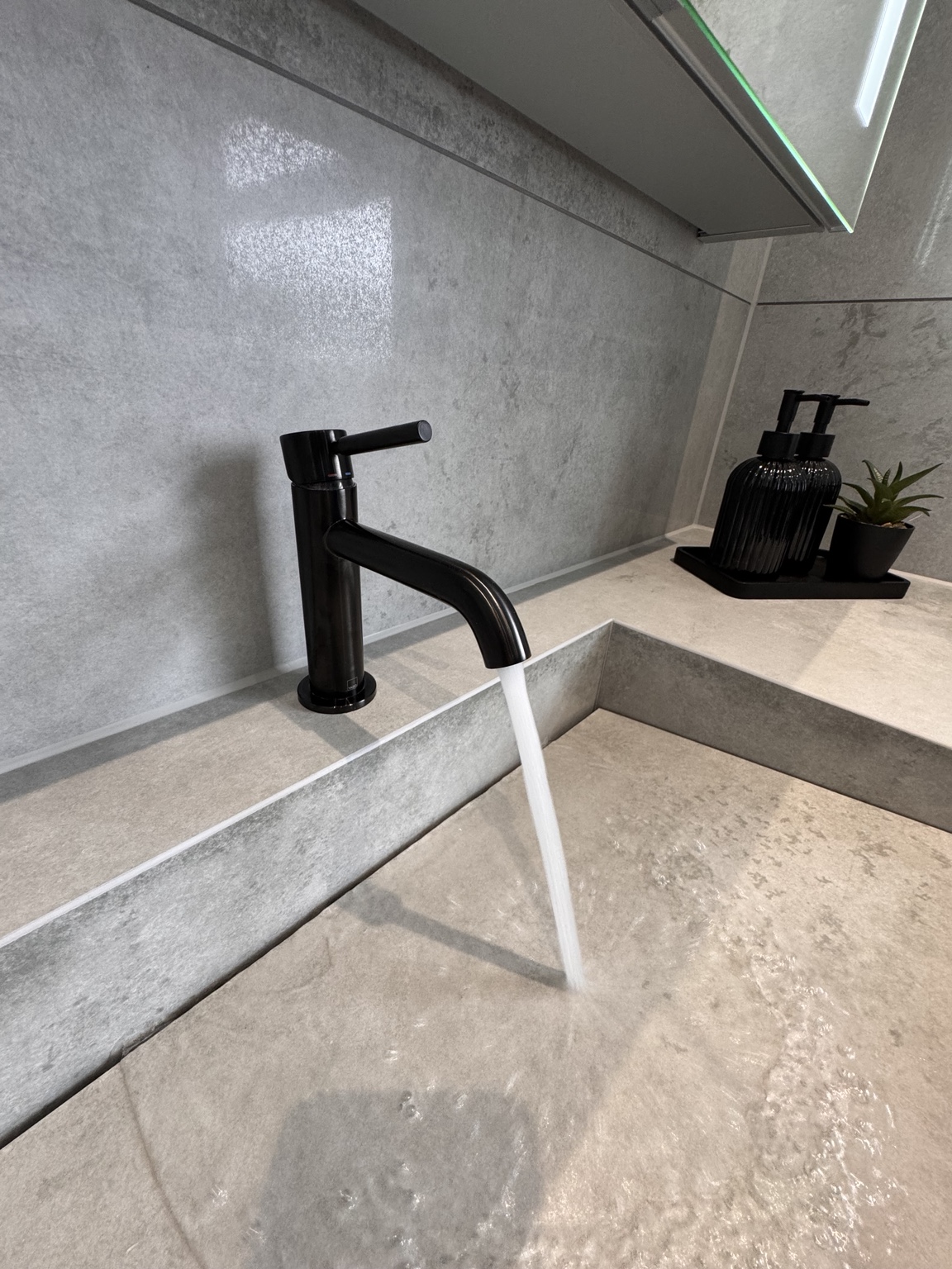 Black tap running into the custom tiled basin